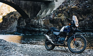 Royal Enfield Himalayan Adventure Motorcycle Parked on Rocky Riverbank Under Stone Bridge HD wallpaper