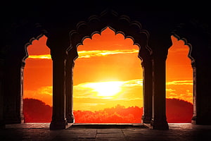 Majestic Indian Palace Arches Framing a Vibrant Orange Sunset Over Distant Hills HD wallpaper