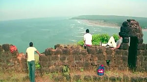 Three friends relaxing on ancient stone ruins overlooking a vast ocean coastline HD wallpaper