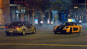 Two modified sports cars drifting on a neon-lit Tokyo street at night HD wallpaper