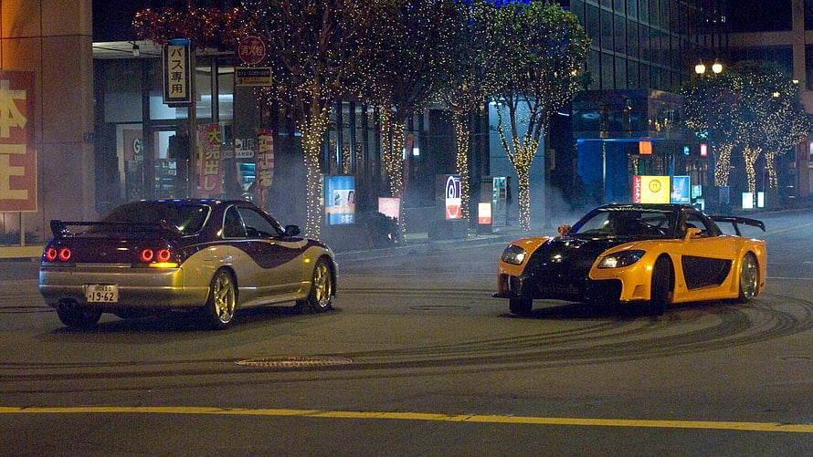 Two modified sports cars drifting on a neon-lit Tokyo street at night HD wallpaper