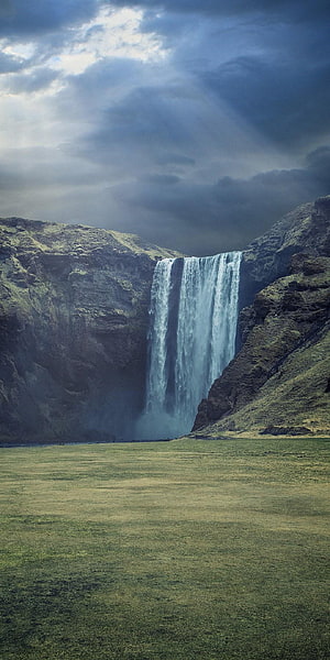 Majestic Skógafoss Waterfall in Iceland with Dramatic Clouds and Green Meadow HD phone wallpaper