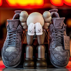 KAWS Companion Figure Flanked by Air Jordan 4 Sneakers in Dark Grey Suede HD phone wallpaper