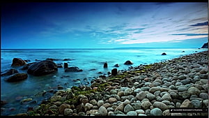Long Exposure Seaside Pebble Beach at Dusk with Smooth Water and Dark Rocks HD wallpaper