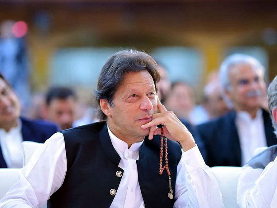 Imran Khan in a black vest and white shirt holding prayer beads in a thoughtful pose HD wallpaper