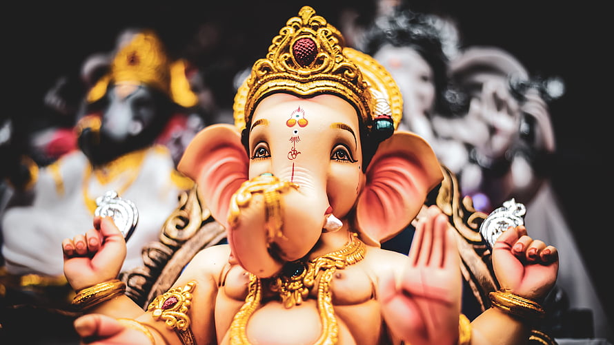 Lord Ganesha Murti with Golden Crown and Traditional Jewelry in Devotional Setting HD wallpaper