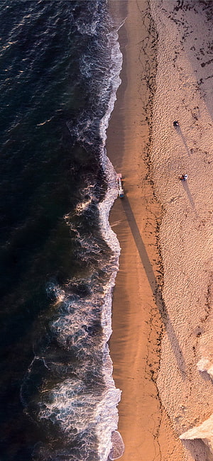 Aerial View of Ocean Waves Crashing on Sandy Beach with Lifeguard Tower HD phone wallpaper