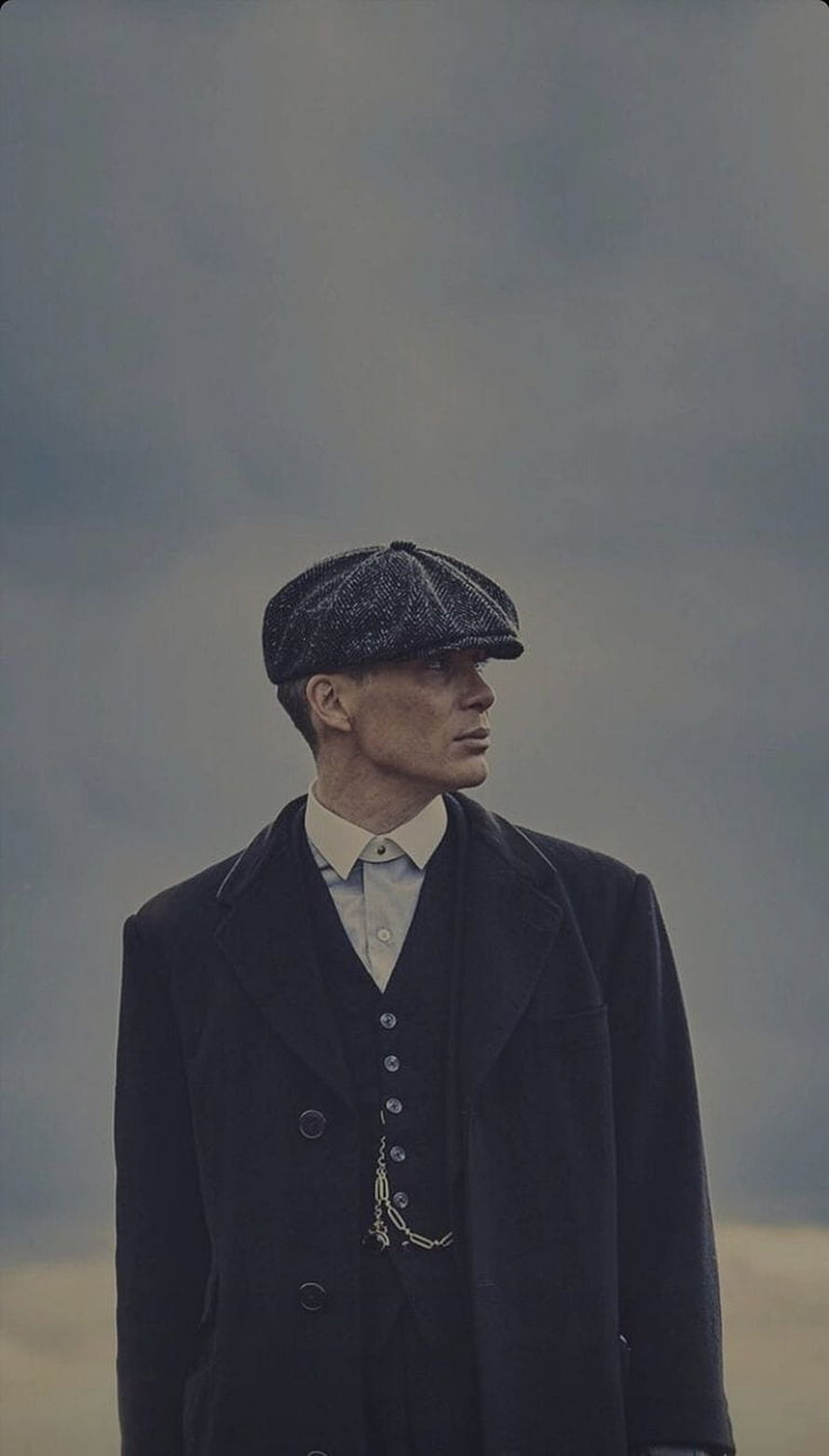 Thomas Shelby from Peaky Blinders wearing flat cap and dark coat against moody sky HD phone wallpaper