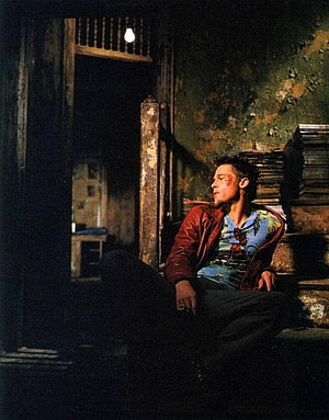 Brad Pitt as Tyler Durden in Fight Club, seated in a dimly lit, dilapidated room HD phone wallpaper