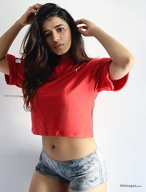 Ketika Sharma in a red crop top and distressed denim shorts posing against a white studio background HD phone wallpaper