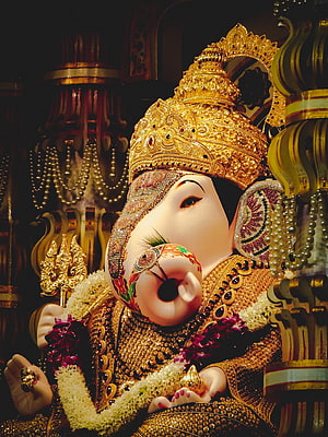 Ornate Lord Ganesha Murti Adorned in Gold Crown and Floral Garlands HD phone wallpaper