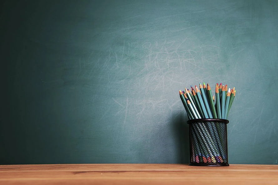 Colored Pencils in Metal Holder Against Green Chalkboard for Back to School Concept HD wallpaper