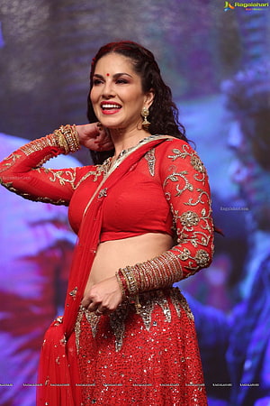 Sunny Leone in a red embroidered lehenga choli with gold jewelry on stage HD phone wallpaper