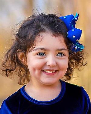 Anahita Hashemzadeh Smiling Portrait with Curly Hair and Blue Bow HD phone wallpaper