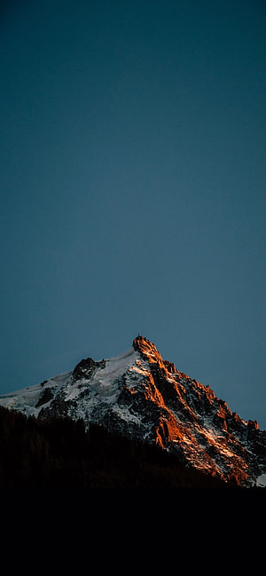 Snow-Capped Mountain Peak Bathed in Golden Sunset Light Against a Deep Blue Sky HD phone wallpaper