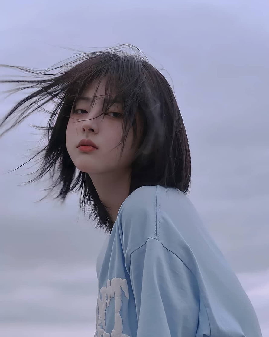 Justina Xie Aesthetic Portrait With Windblown Hair and Soft Blue Shirt HD phone wallpaper