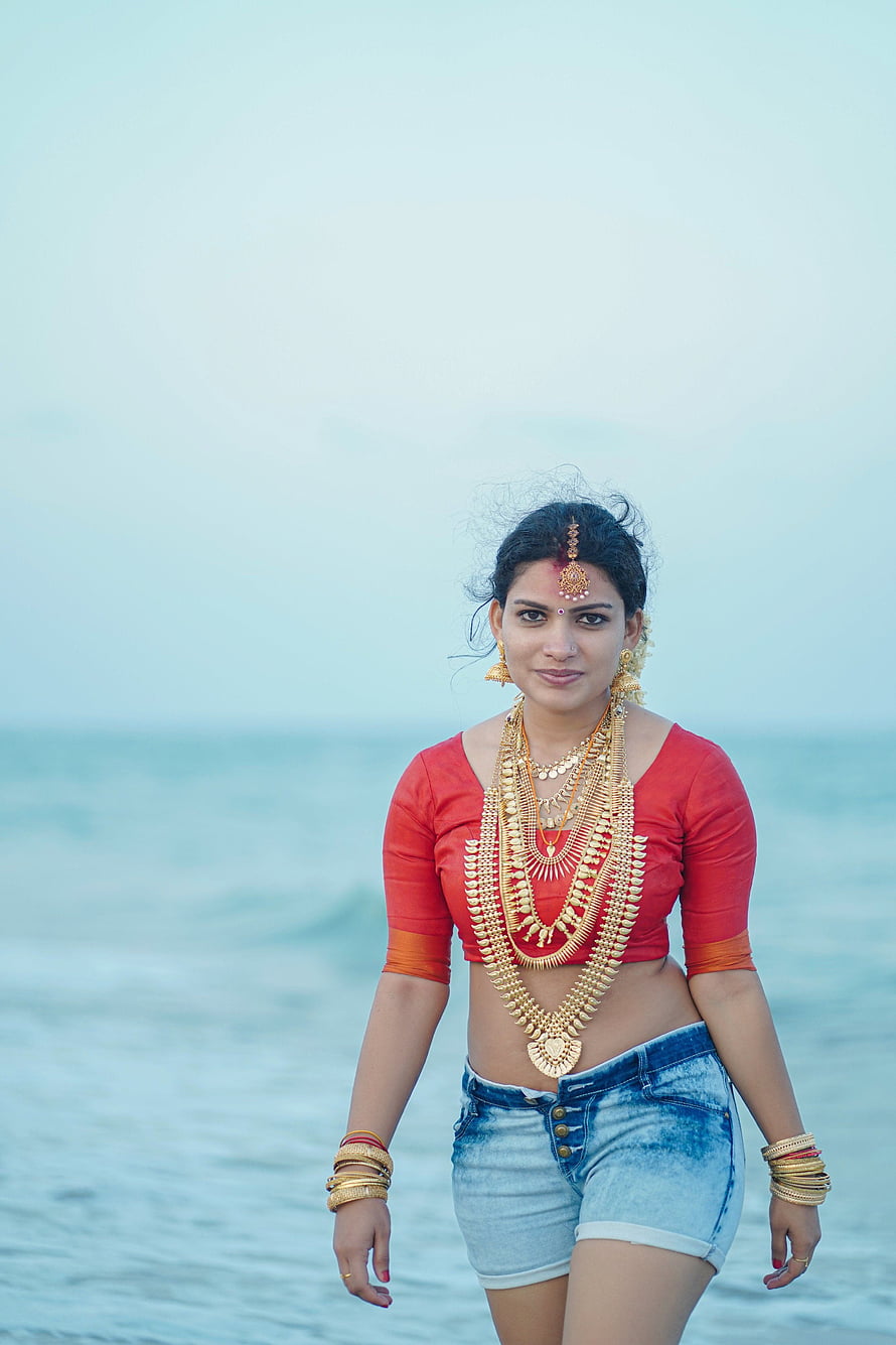 Reshmi Nair in Traditional Gold Jewelry and Red Top on the Beach HD phone wallpaper