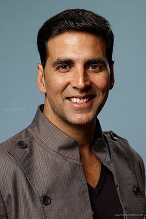 Akshay Kumar smiling portrait in a textured grey jacket against a muted blue studio backdrop HD phone wallpaper