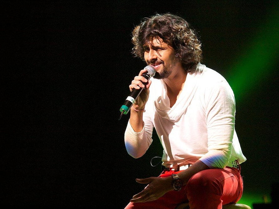 Sonu Nigam performing live on stage in a white shirt and red pants holding a microphone HD wallpaper