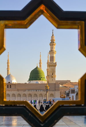Al-Masjid an-Nabawi in Medina framed by an ornate golden Islamic geometric window HD phone wallpaper