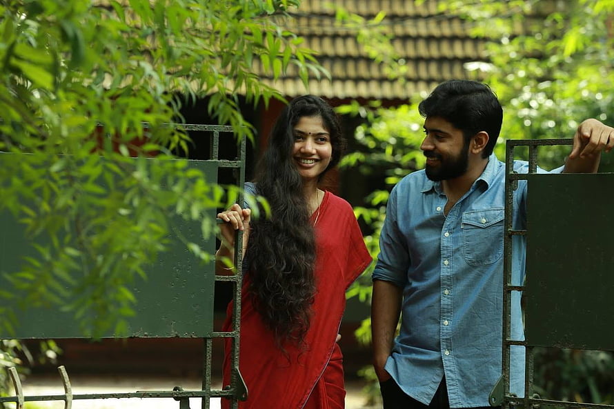 Premam Movie Still Featuring Manju Warrier and Dusharanthan in a Lush Garden Setting HD wallpaper