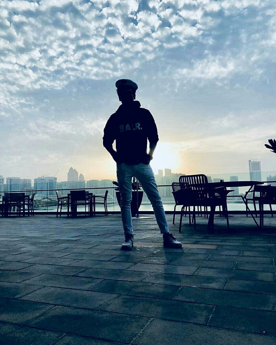 Silhouette of a man in a cap and hoodie standing on a rooftop terrace overlooking a city skyline at sunset, Whatsapp DP in 2021, instagram dp boys HD phone wallpaper