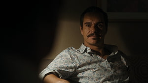 Lalo Salamanca in a dimly lit room wearing a patterned shirt with a serious expression HD wallpaper