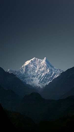 Majestic Snow-Capped Mountain Peak Rising Above Dark Forested Valleys HD phone wallpaper