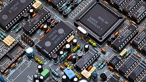 Close-up of a densely populated printed circuit board with integrated circuits and electronic components HD wallpaper