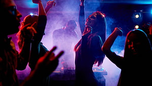 Energetic crowd dancing under vibrant neon lights in a smoky nightclub atmosphere HD wallpaper