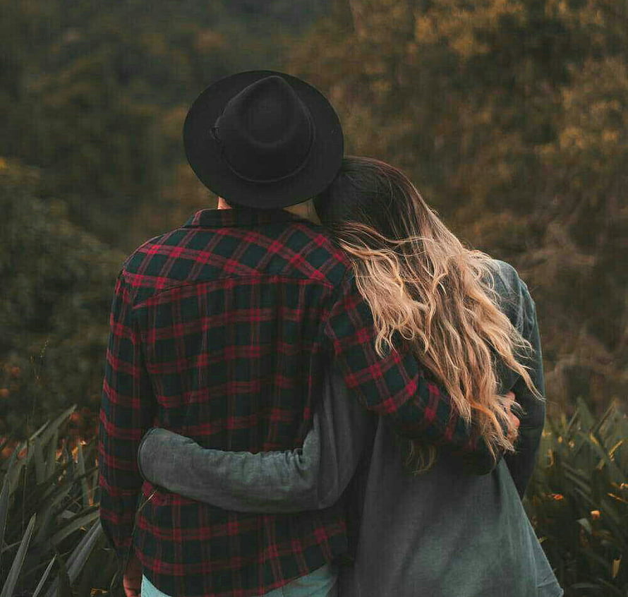 Couple Embracing in Autumn Forest with Plaid Shirt and Fedora Hat HD wallpaper