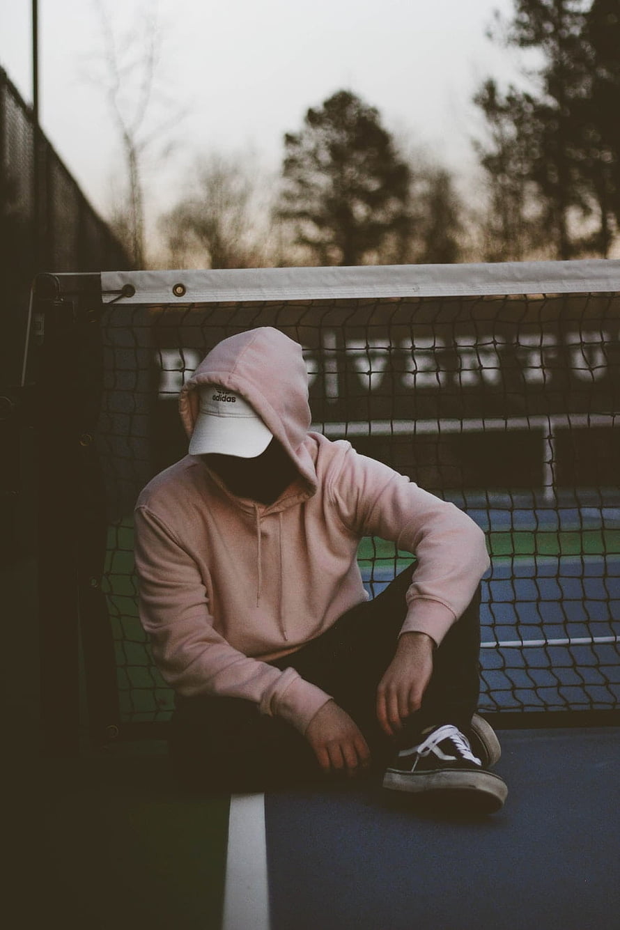 Person in Pink Hoodie and White Cap Sitting on Tennis Court HD phone wallpaper
