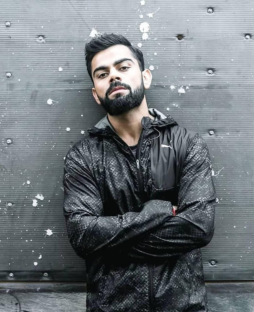 Virat Kohli in Black Puma Jacket with Arms Crossed Against Industrial Wall HD phone wallpaper
