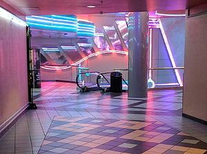 Neon-lit interior corridor with geometric tile floor and glowing architectural accents HD wallpaper