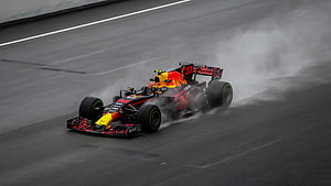 Red Bull Racing Formula 1 car drifting through wet track spray HD wallpaper
