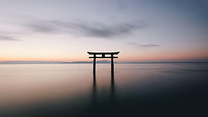 Serene Torii Gate Standing in Calm Water at Sunset HD wallpaper