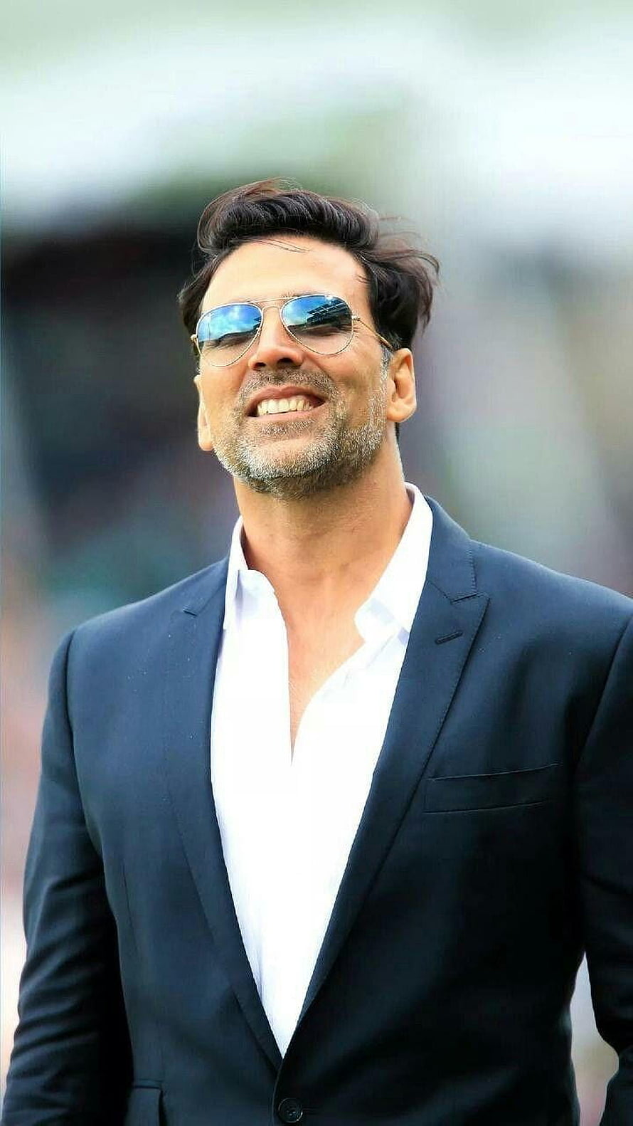 Akshay Kumar in a navy suit and aviator sunglasses with a confident smile HD phone wallpaper
