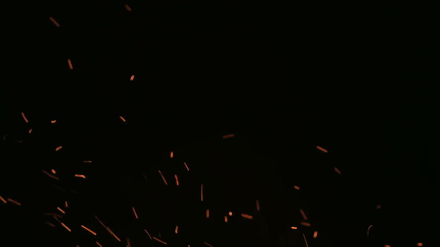 Glowing Orange Sparks Flying Against a Pitch Black Background HD wallpaper