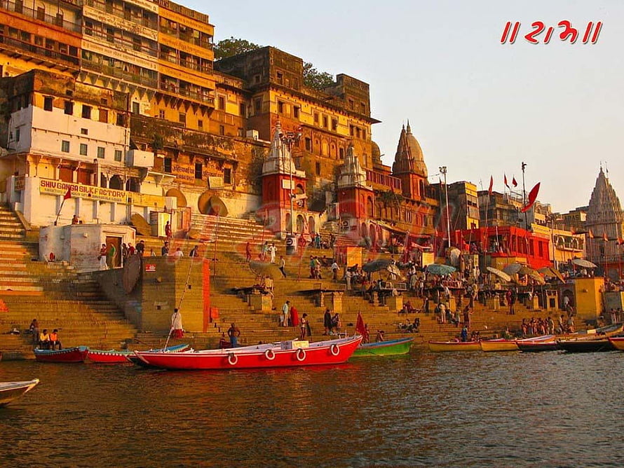 Varanasi Ghat at Golden Hour with Colorful Boats and Temple Architecture HD wallpaper