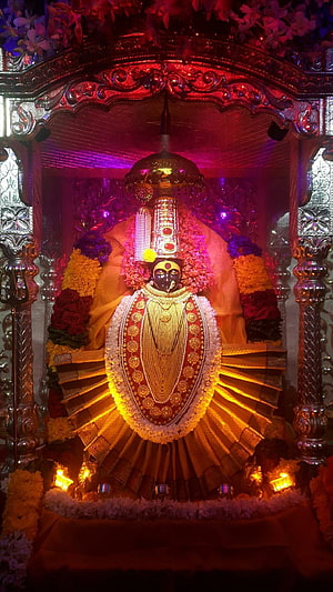 Ornate Hindu Deity Statue Adorned with Gold Jewelry and Flower Garlands in Temple Shrine HD phone wallpaper
