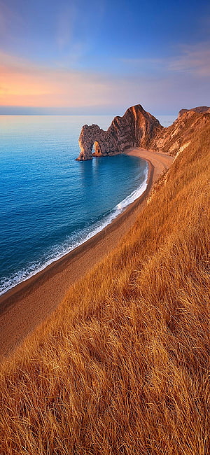 Durdle Door Limestone Arch at Sunset, Dorset Coastline with Golden Grass and Blue Ocean HD phone wallpaper
