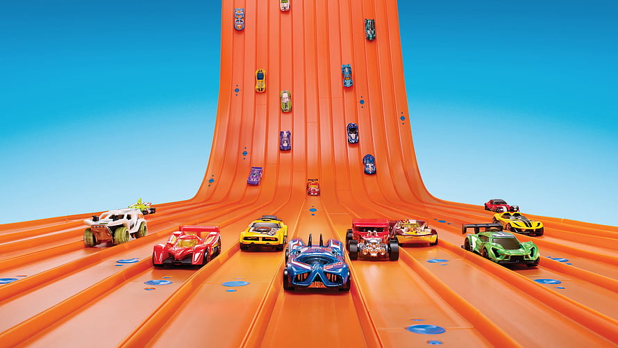 Hot Wheels toy cars racing down a giant orange track against a clear blue sky HD wallpaper