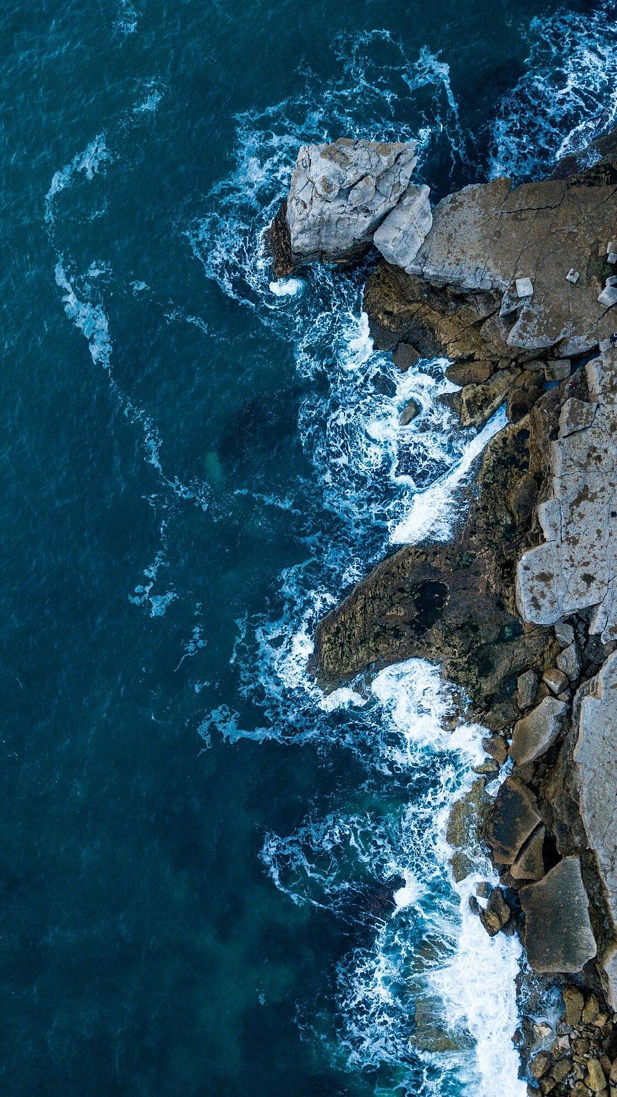 Aerial View of Turquoise Ocean Waves Crashing Against Rocky Coastline HD phone wallpaper