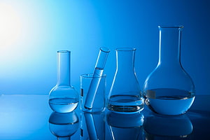 Blue Tinted Chemistry Laboratory Glassware with Beakers and Flasks on Reflective Surface HD wallpaper