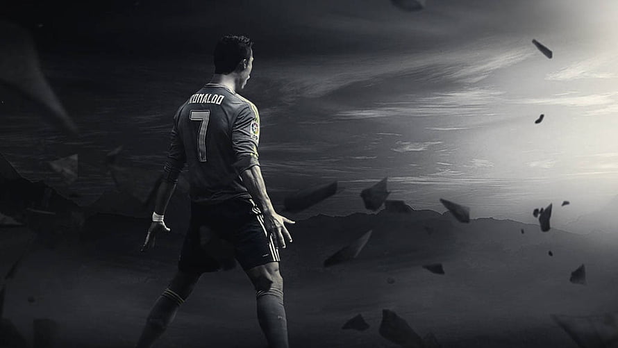 Cristiano Ronaldo in dark jersey standing in a dramatic monochrome landscape with floating debris HD wallpaper