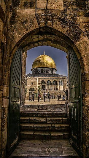 Dome of the Rock in Jerusalem viewed through an ancient stone archway with green wooden doors HD phone wallpaper