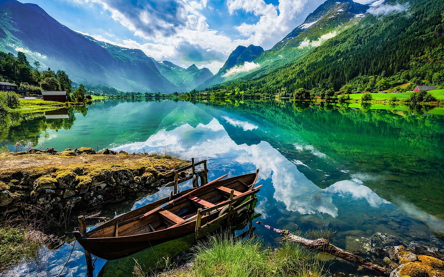 Serene wooden boat docked at a crystal-clear fjord with majestic green mountains and perfect sky reflections HD wallpaper