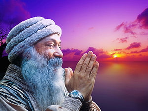 Osho in Prayer at Sunset with Hands Folded Against a Vibrant Ocean Sky HD wallpaper