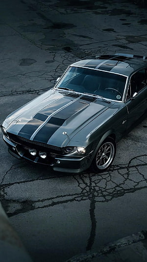 Classic Ford Mustang Shelby GT500 with racing stripes parked on cracked asphalt HD phone wallpaper