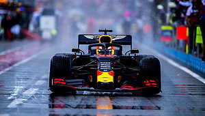 Red Bull Racing Formula 1 car speeding on a wet track during a rain-soaked race HD wallpaper